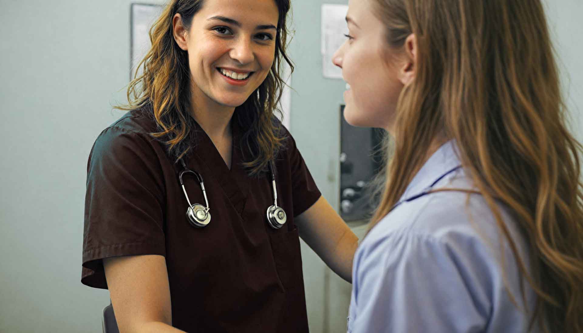 A friendly doctor is smiling and discussing a general wellness exam with her patient.